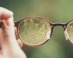 hands  holding eyeglasses showing a different vision